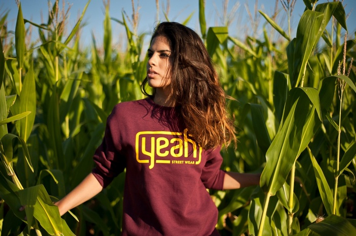 Woman in a cornfield wearing a maroon sweatshirt