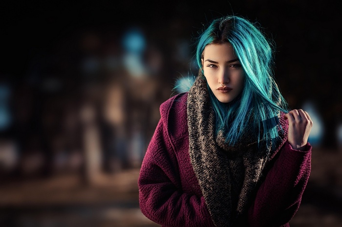 Woman with blue dyed hair wearing a scarf and coat