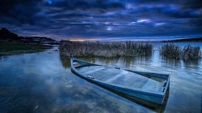 Sunken boat in a calm lake at dusk