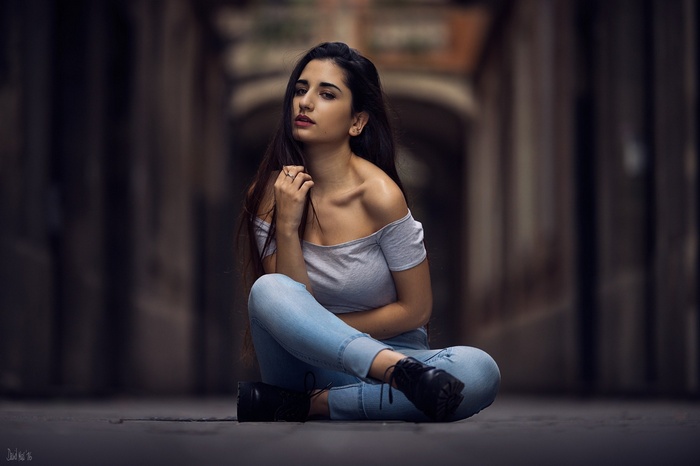 Woman with long dark hair sitting on the ground