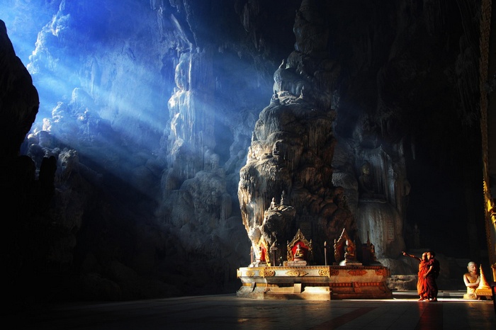 Monks in a cave temple with sun rays