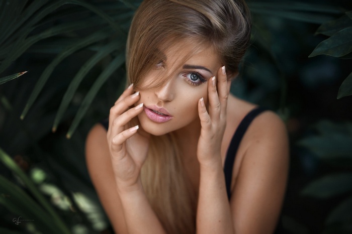 Portrait of a blonde woman with hands near face
