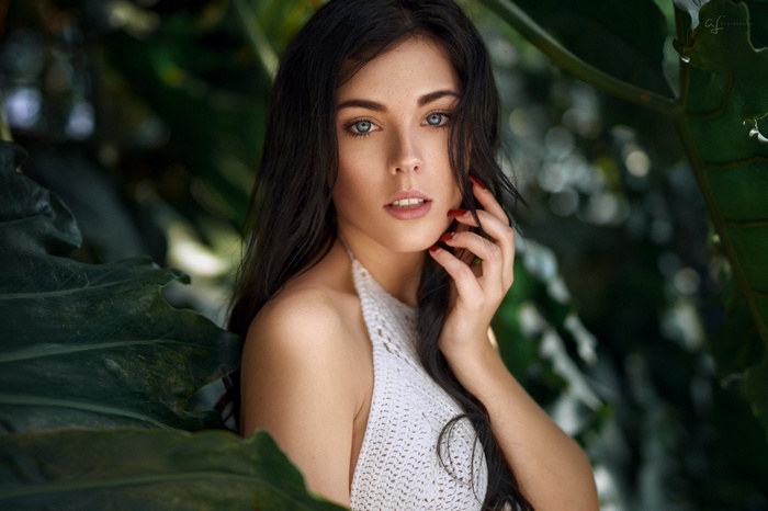 Woman with dark hair and blue eyes in foliage