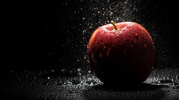 Red apple with water drops on black background