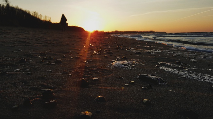 Beach at sunset with people walking