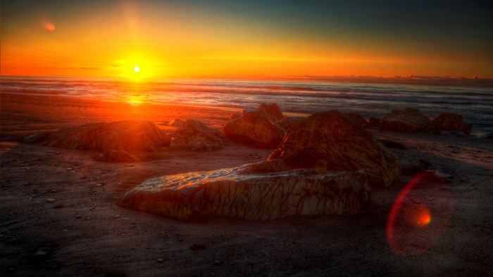 Sunset over a rocky beach with ocean waves