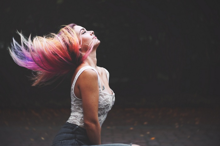 Woman with colorful hair tossing her head outdoors