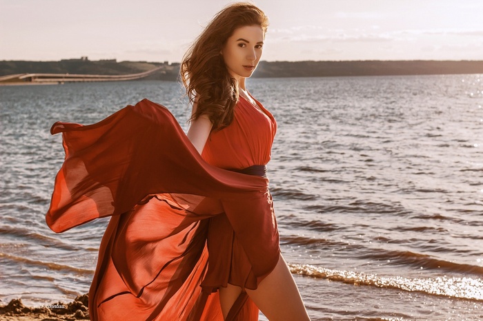 Woman in red dress on beach at sunset