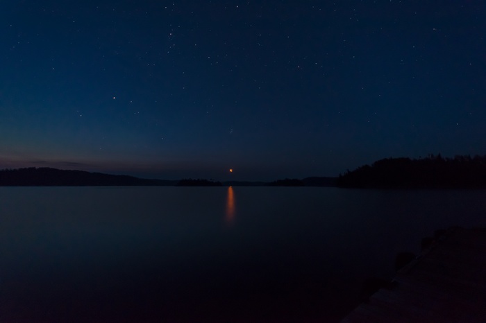 Night sky over a lake with stars and moon