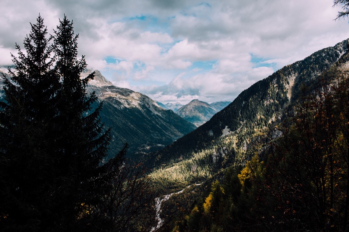 Mountains and trees with snow under a cloudy sky