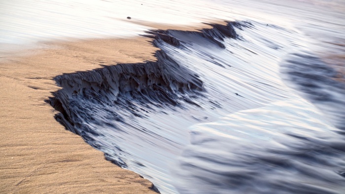 Long exposure of waves crashing on a sandy shore