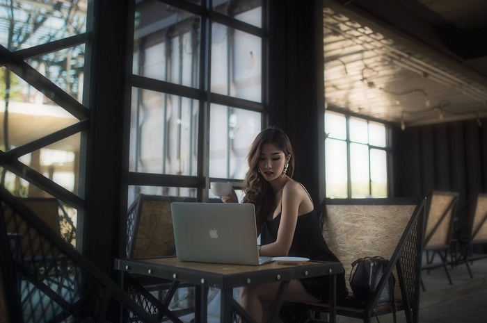 Asian woman with MacBook and coffee at a cafe