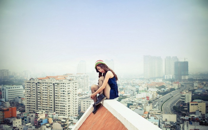 Woman sitting on a rooftop overlooking a cityscape