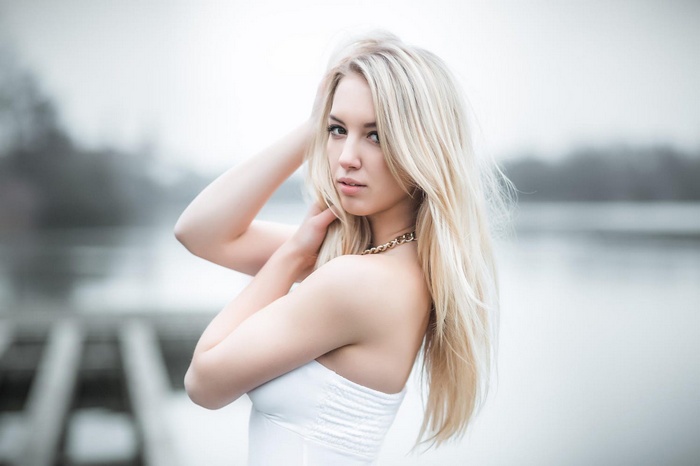 Woman with platinum blonde hair by a lake