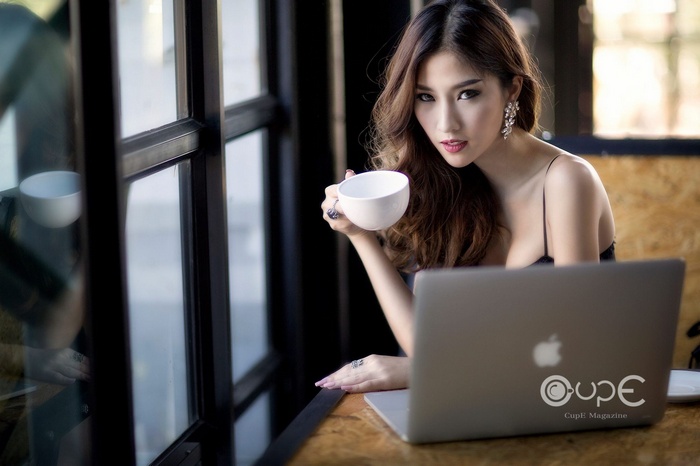 Asian woman holding a cup with a laptop