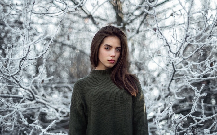 Woman in a green sweater in a winter forest