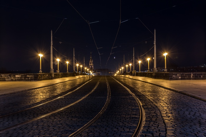 Cobblestone bridge with tram tracks and street lights at night