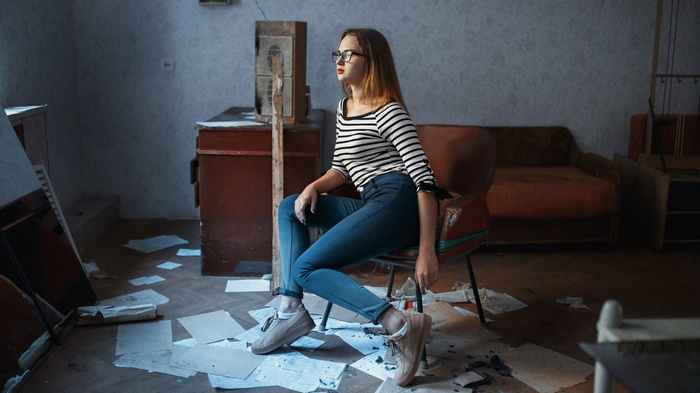Woman with glasses sitting in a chair in a room