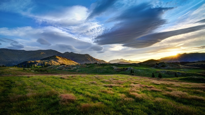 Rolling green hills and mountains at sunset