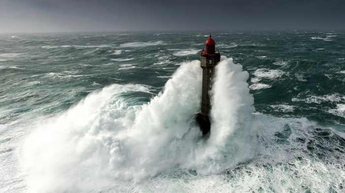 Lighthouse battered by massive waves during a storm