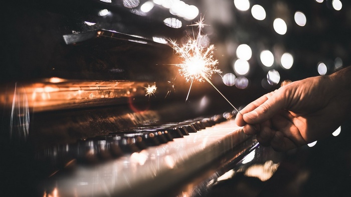 Sparkler held over piano keys with bokeh lights