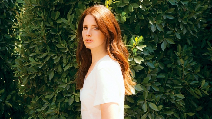 Lana Del Rey in front of green foliage