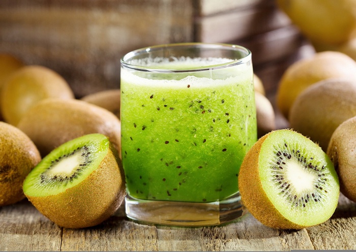 Kiwi smoothie with fresh kiwis on a wooden table