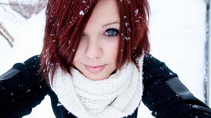 Young woman with red hair and blue eyes in the snow