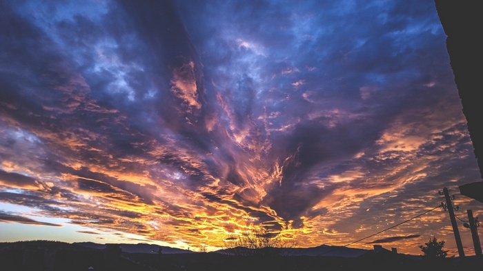 Dramatic sunset sky with clouds over a silhouetted landscape