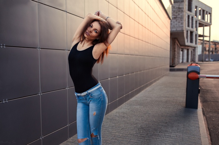 Woman with auburn hair in torn jeans