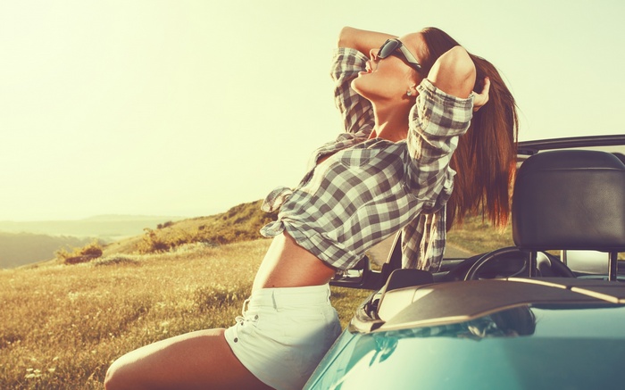 Woman in sunglasses and checkered shirt in a convertible