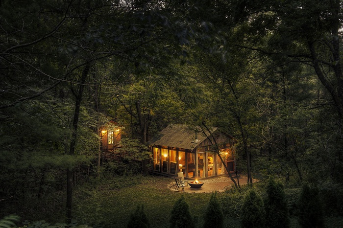 Cozy cabins in a dark forest with a campfire