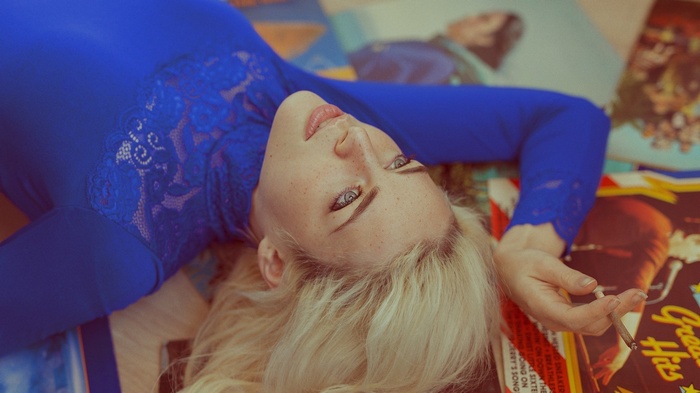 Woman with blonde hair wearing blue top lying down
