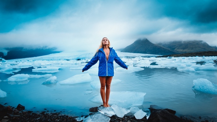 Woman in blue jacket standing on ice in Iceland