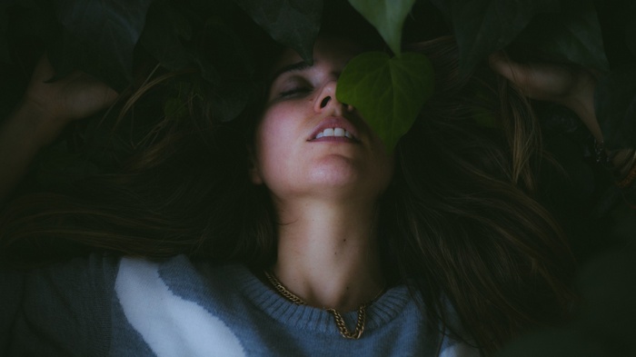 Woman lying down with leaves covering her face
