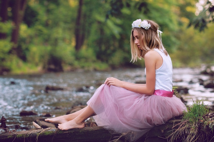 Girl with flower crown and pink skirt by stream