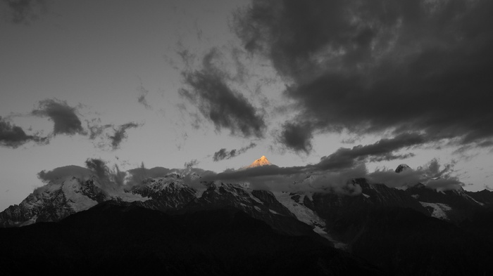Snowy mountain peak illuminated by sunlight through clouds