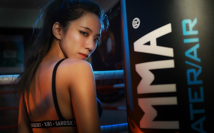 Asian woman in boxing ring with MMA bag
