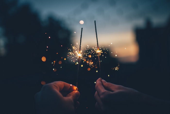 Hands holding sparklers at dusk