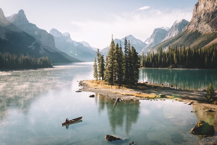 Canoe on a misty lake with mountains and pine trees