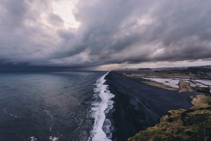 Black sand beach with stormy clouds and ocean waves