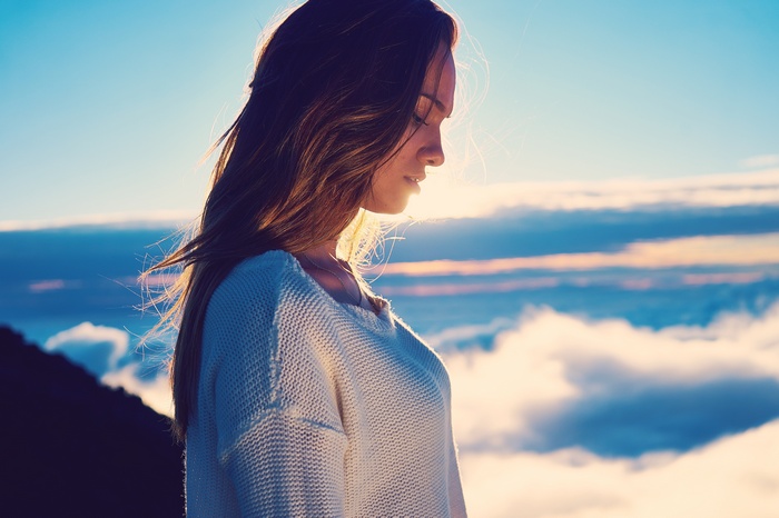 Woman with long hair wearing a sweater above clouds