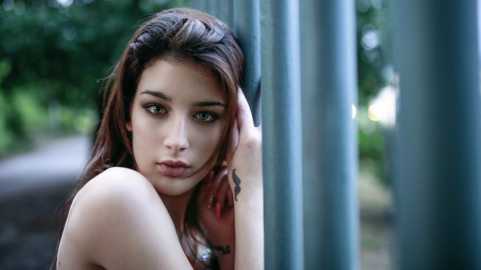 Woman leaning against a fence outdoors