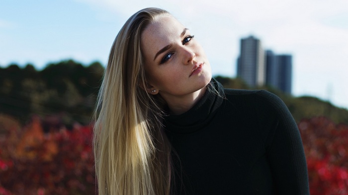 Blonde woman outdoors with buildings in background