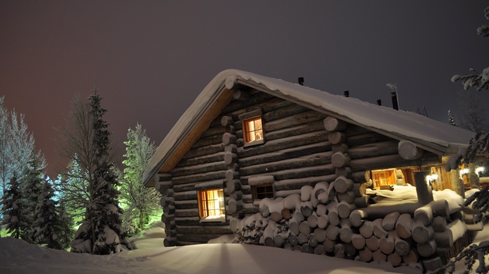 Snowy log cabin at night with warm lights