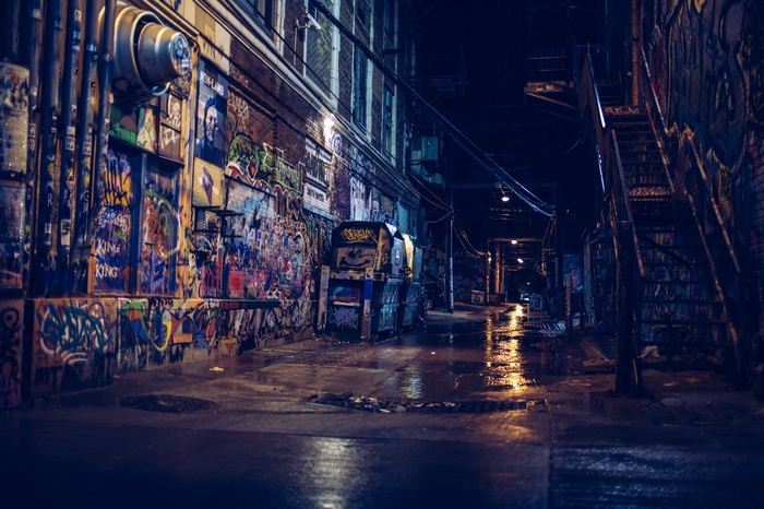 Graffiti-covered alleyway at night with reflections