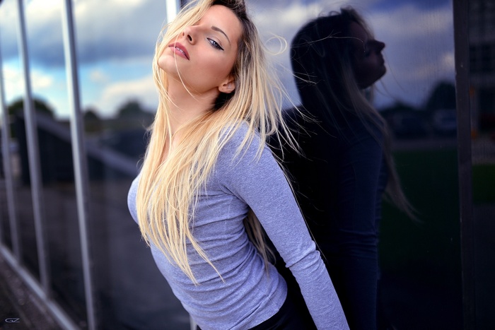 Woman with blonde hair leaning against a reflective surface