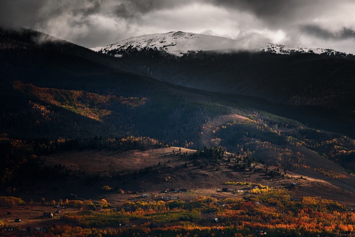 Snow-capped mountain range with autumn foliage and scattered houses