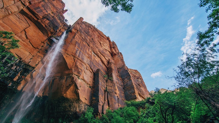 Waterfall cascading down a massive red rock cliff in Zion National Park