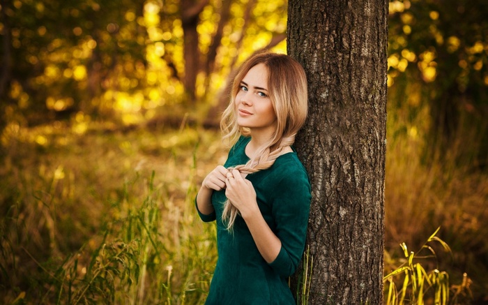 Woman leaning against a tree in a forest